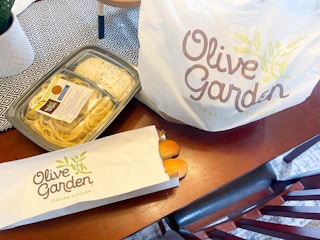 A to-go order from Olive Garden on a dining room table.