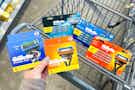 hand hold gillette razor blade cartridge refills with more in a cart in the background