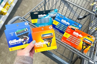 hand hold gillette razor blade cartridge refills with more in a cart in the background