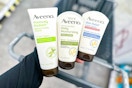 person holding aveeno skincare products over a cart