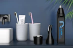 a nose hair trimmer on a bathroom sink with toothbrushes and toothpaste