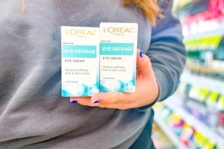 person holding 2 loreal eye creams in front of their body