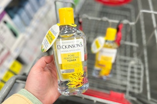 hand holding a bottle of dickinson's witch hazel toner over a cvs cart