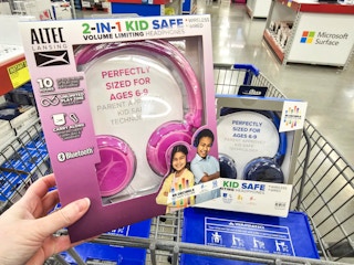 person holding a pair of pink headphones over a cart with blue headphones in it
