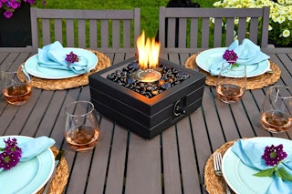 Lifestyle image of the allen + roth Tabletop Fire Pit on an outdoor table with dining setting