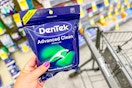 person holding a package of dentek floss picks over a walgreens cart