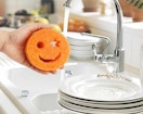 a person using an orange dish sponge