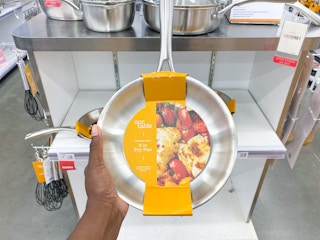 Hand holding up stainless steel fry pan