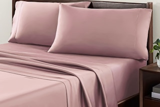 Lifestyle image of the Allswell 4-piece sheet set in the color "Mauve" on a bed in room setting