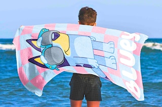 Lifestyle image of the kids' Bluey towel being used at the beach