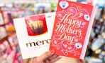 hand holding a box of chocolates and mother's day card in store aisle