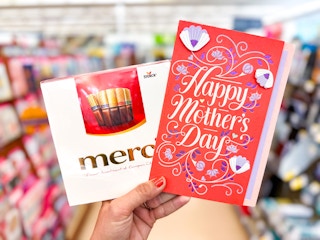 hand holding a box of chocolates and mother's day card in store aisle