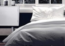 a grey comforter on a bed in a room