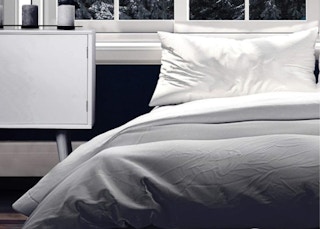 a grey comforter on a bed in a room