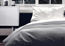 a grey comforter on a bed in a room