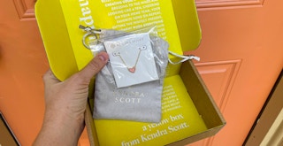 a person holding a kendra scott necklace