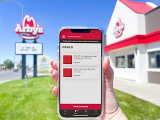 a cellphone being held in front of arbys in front with the arbys app deal page 