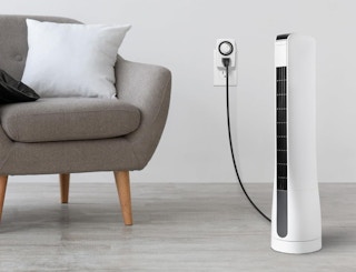 a fan plugged into an outlet next to a chair