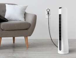 a fan plugged into an outlet next to a chair