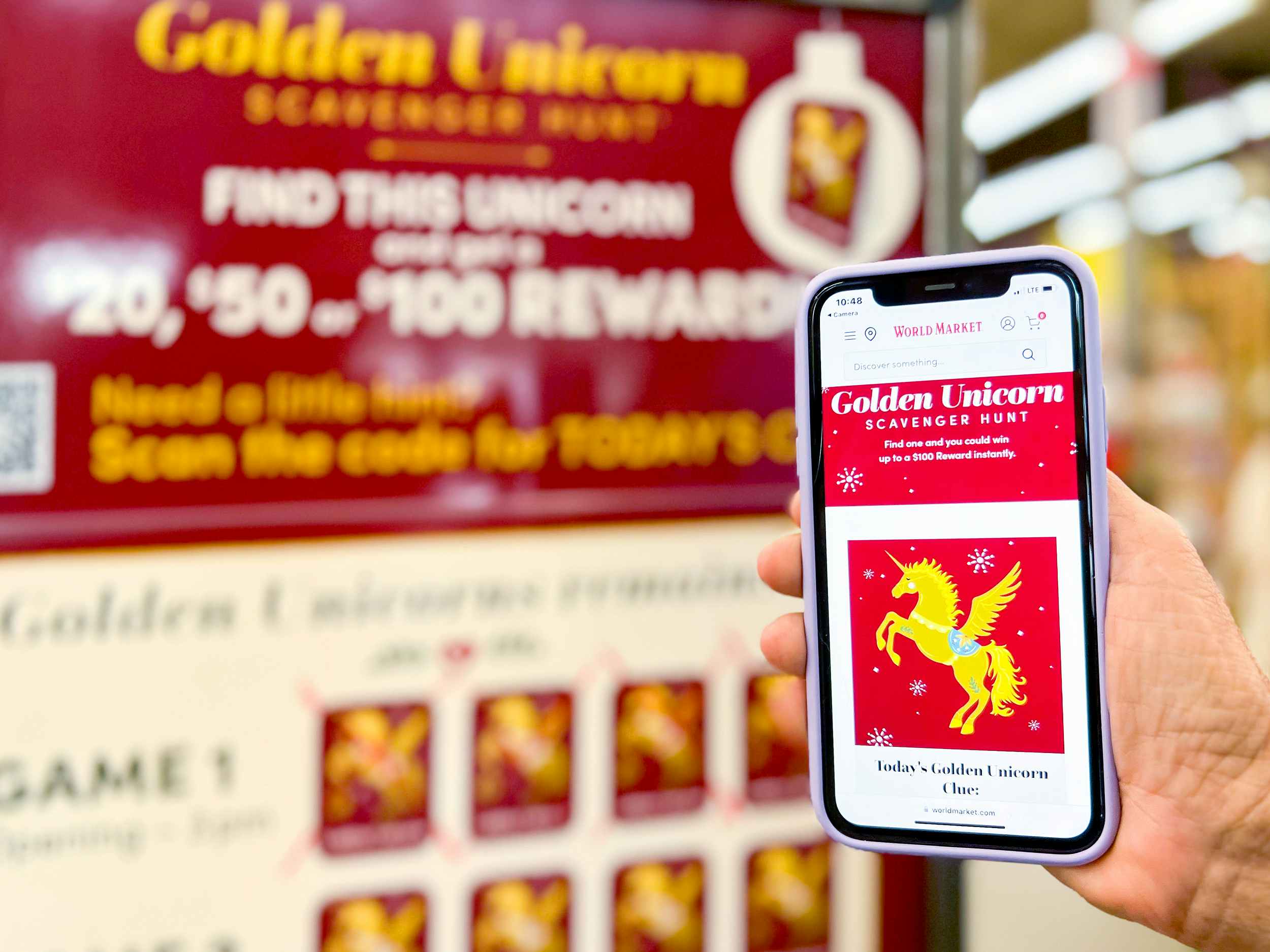 hand holding a phone next to world market golden unicorn scavenger hunt signage