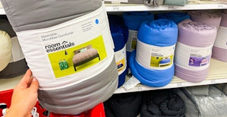 hand holding a room essentials microfiber comforter in front of a target shelf with bedding items