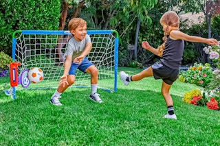 Lifestyle image of the Little Tikes Sports Game Kit: 2 kids' playing soccer outdoors