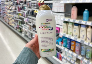 hand holding ogx coconut miracle oil body wash in an aisle in a store