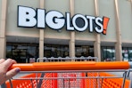 Hand pushing an orange Big Lots shopping cart into the store