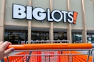 Hand pushing an orange Big Lots shopping cart into the store