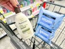 person placing a bottle of aveeno lotion in a cart with neutrogena makeup wipes in it