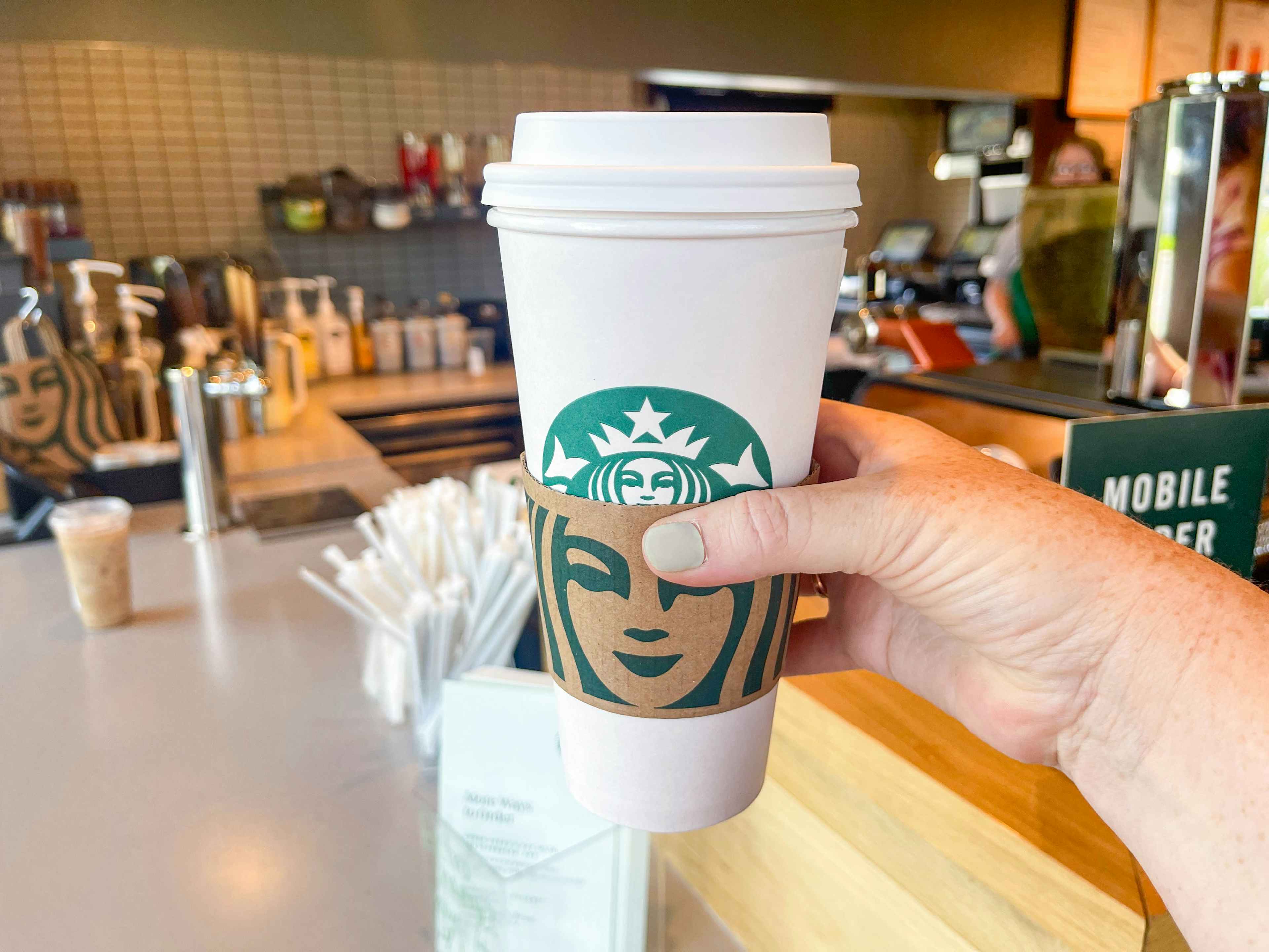 person holding a large starbucks hot beverage in store