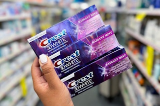 hand holding three boxes of Crest 3D White toothpaste