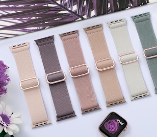 earth-toned Apple Watch bands on a table next to an Apple Watch