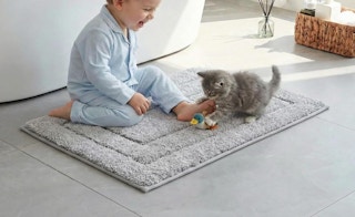 a kid and kitchen playing on a bathroom rug