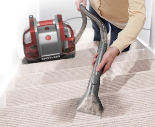 A person cleaning their carpet staircase with the Hoover Spotless.