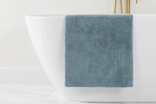a grey bath mat on a bathtub