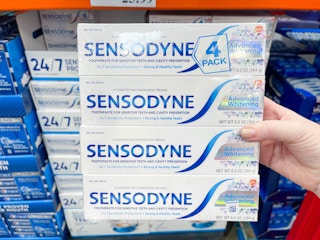 four boxes of toothpaste packaged together being held in store