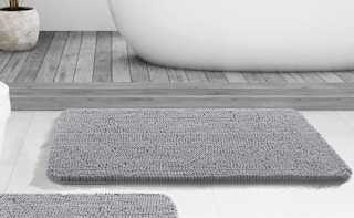 a grey rug in a bathroom in front of a bathtub 