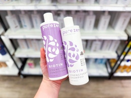 hand holding a bottle of PureZero shampoo and a bottle of conditioner