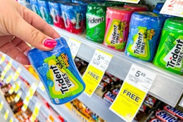 person holding a container of trident gum by the display
