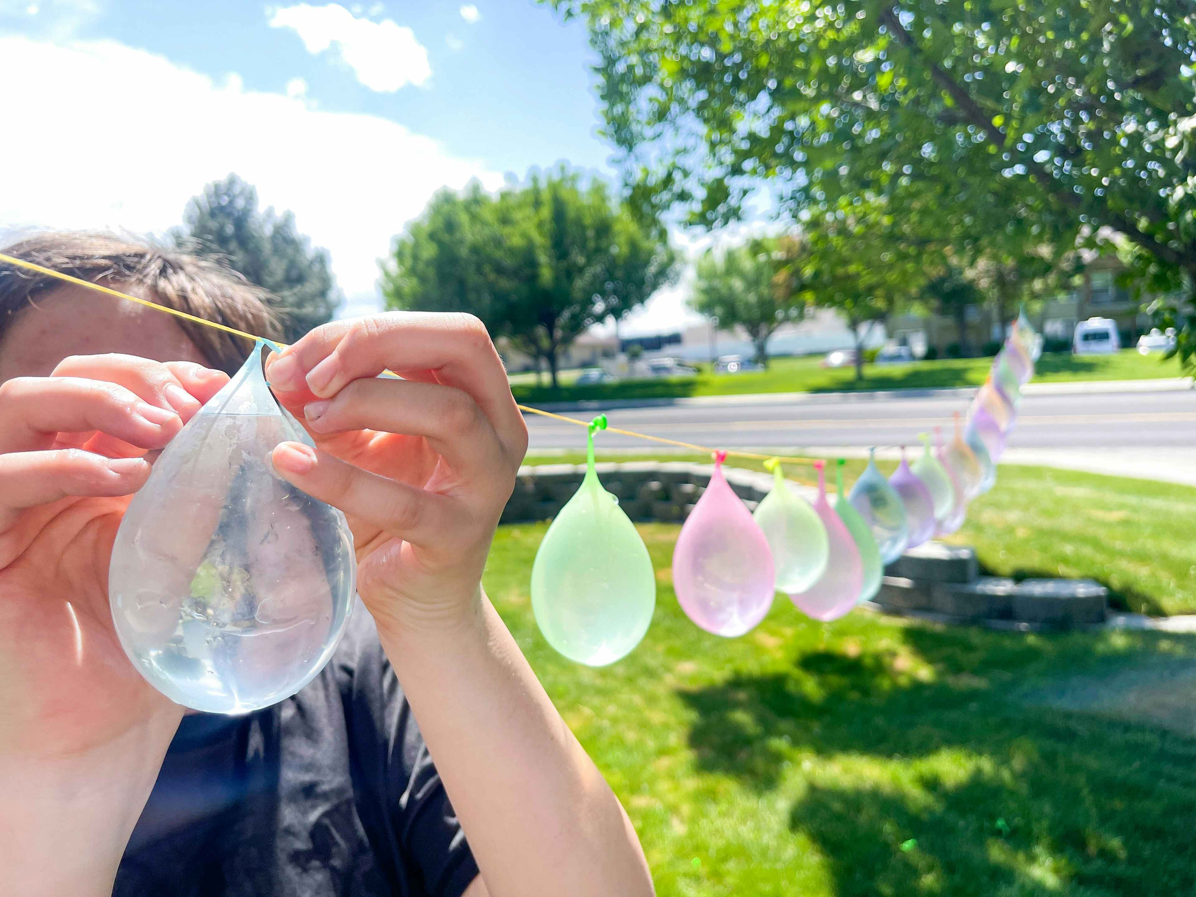 a person tying water balloons to a string 