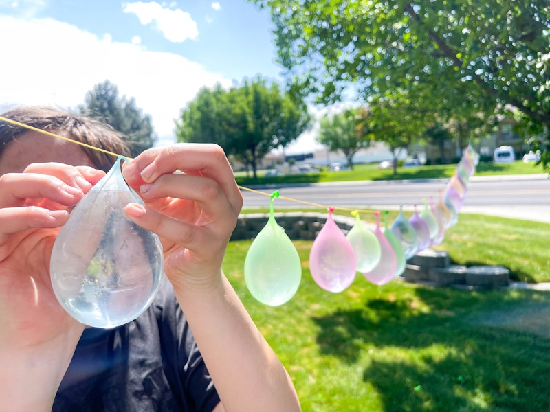 a person tying water balloons to a string 