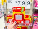 hand holding an etch a sketch pocket toy in front of target signage