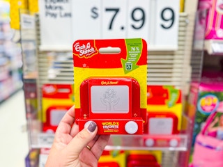 hand holding an etch a sketch pocket toy in front of target signage