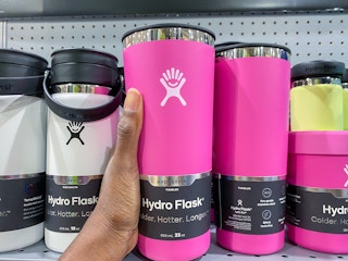 a hydroflask being held in front of a display of other hydrflasks