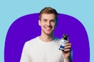 A young man with light brown hair in a white t-shirt holds a bottle (jar?) of men's multivitamins, which are gluten free & increase vitality