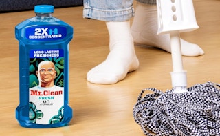 a bottle of cleaner on the floor next to a mop