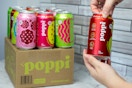 a pack of Poppi soda next to someone opening a can