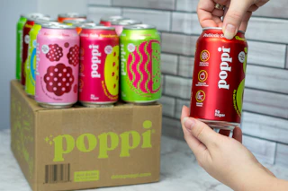 a pack of Poppi soda next to someone opening a can