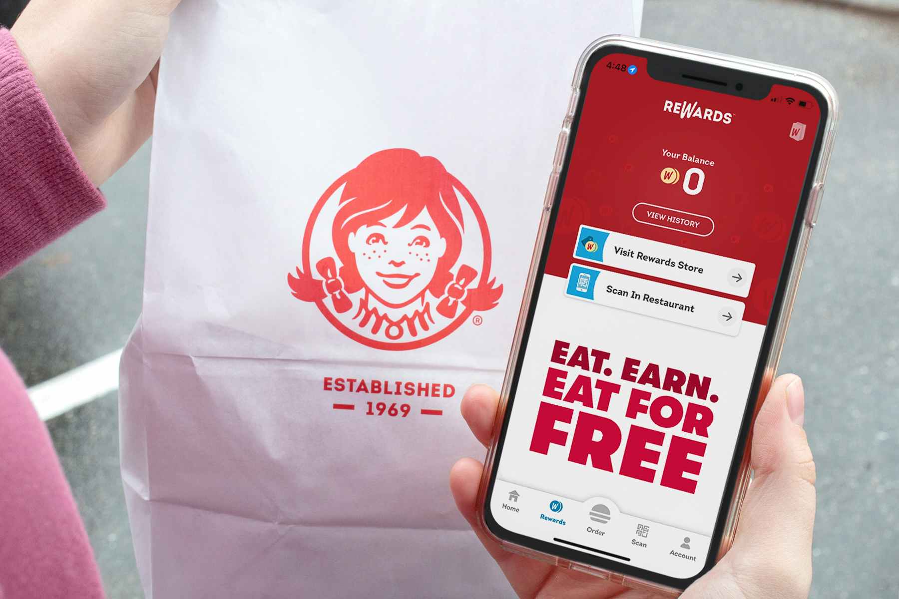 A person holding their phone displaying the Wendy's rewards app
